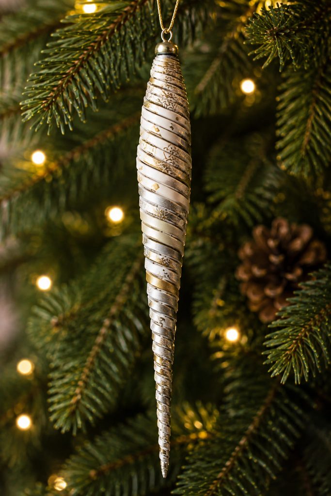 Tapered rolled paper icicle ornament with fine spiral ridges on a narrow tree branch.