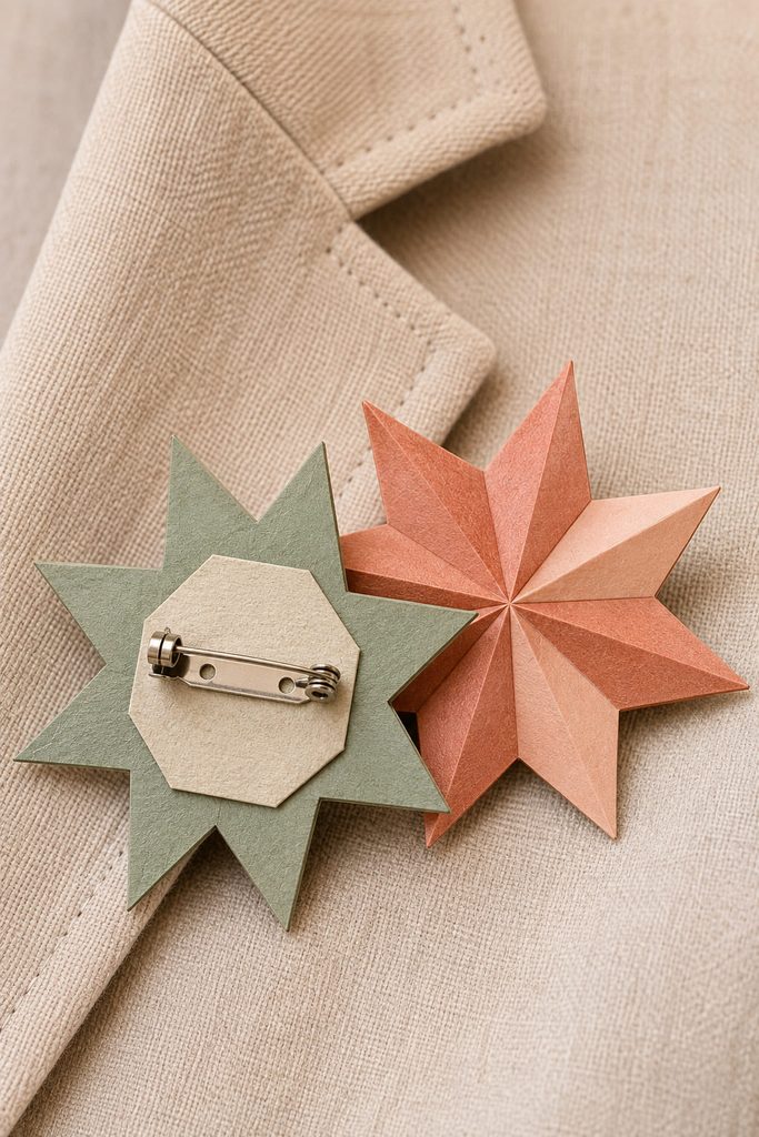 Reinforced paper star brooch with a working pin back beside a fabric lapel.