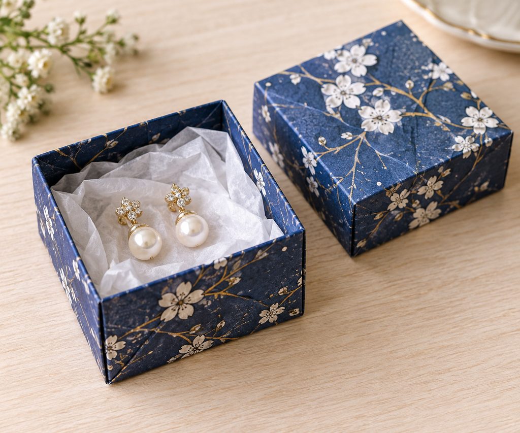Classic lidded origami gift box folded from indigo patterned paper with earrings inside.