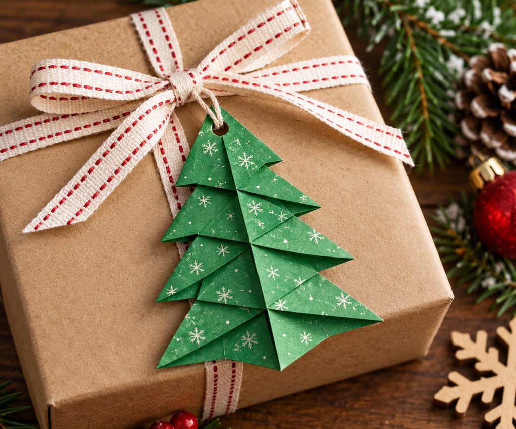 Christmas origami tree gift tag folded from green paper and tied to a kraft-paper present.