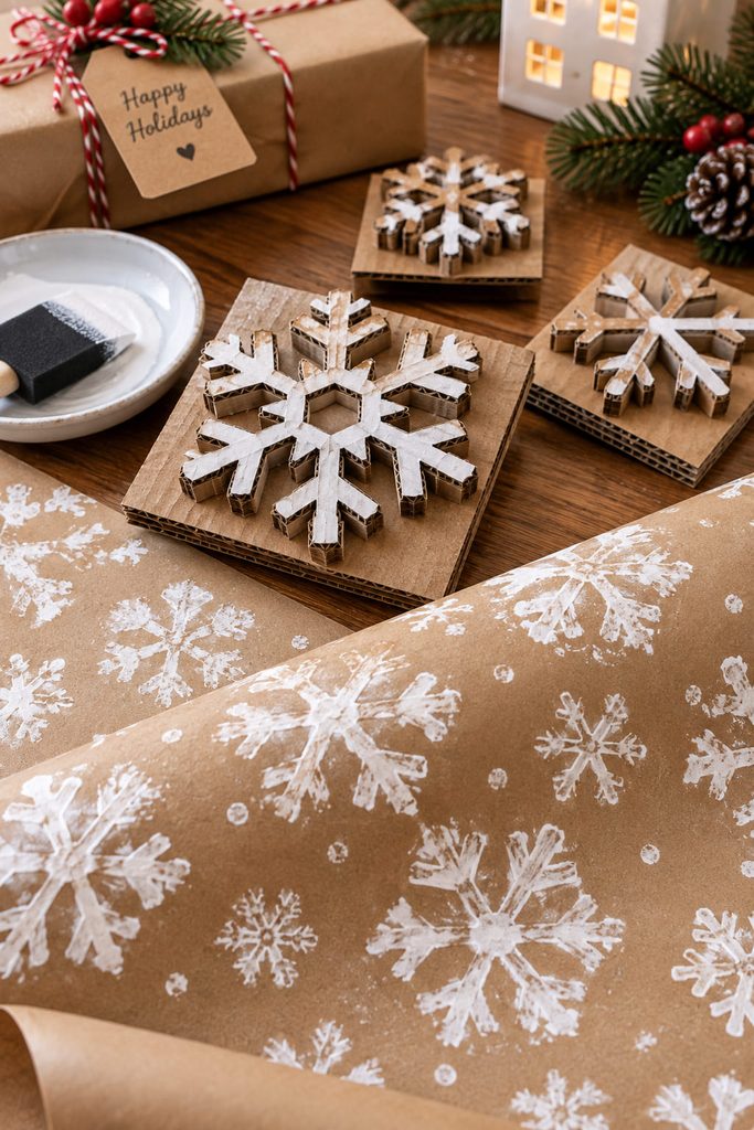 Cardboard snowflake printing blocks beside handmade stamped Christmas wrapping paper.