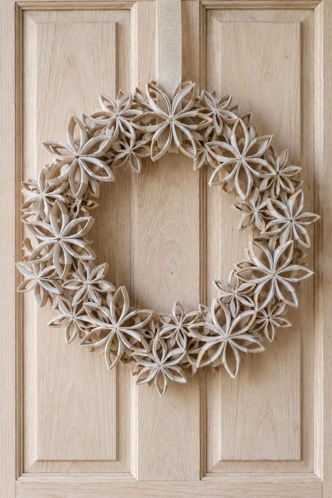 Circular wreath built from overlapping mini cardboard-tube snowflakes on a hidden backing ring.